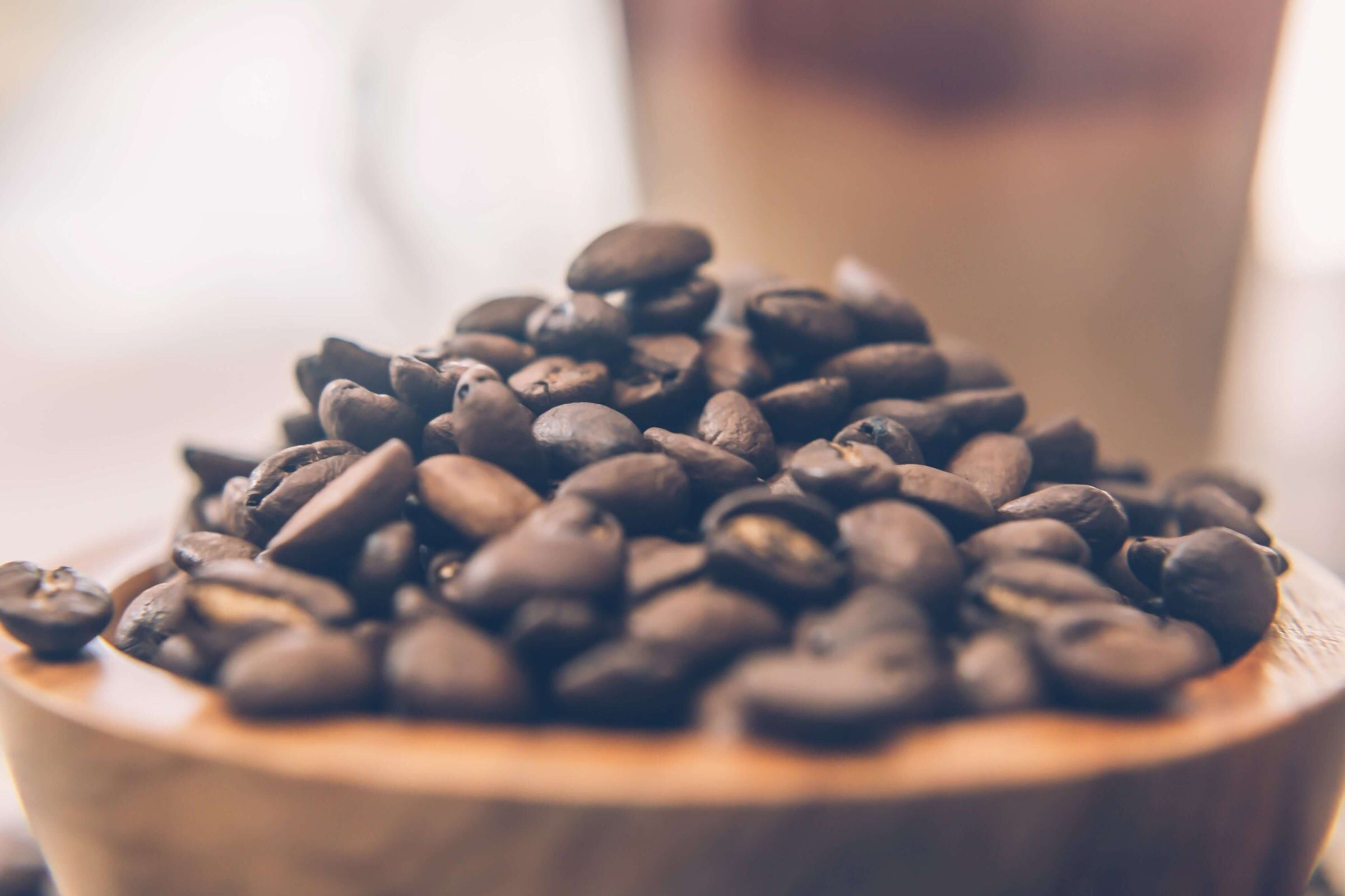 Roasted coffee beans heaped in a wooden bowl