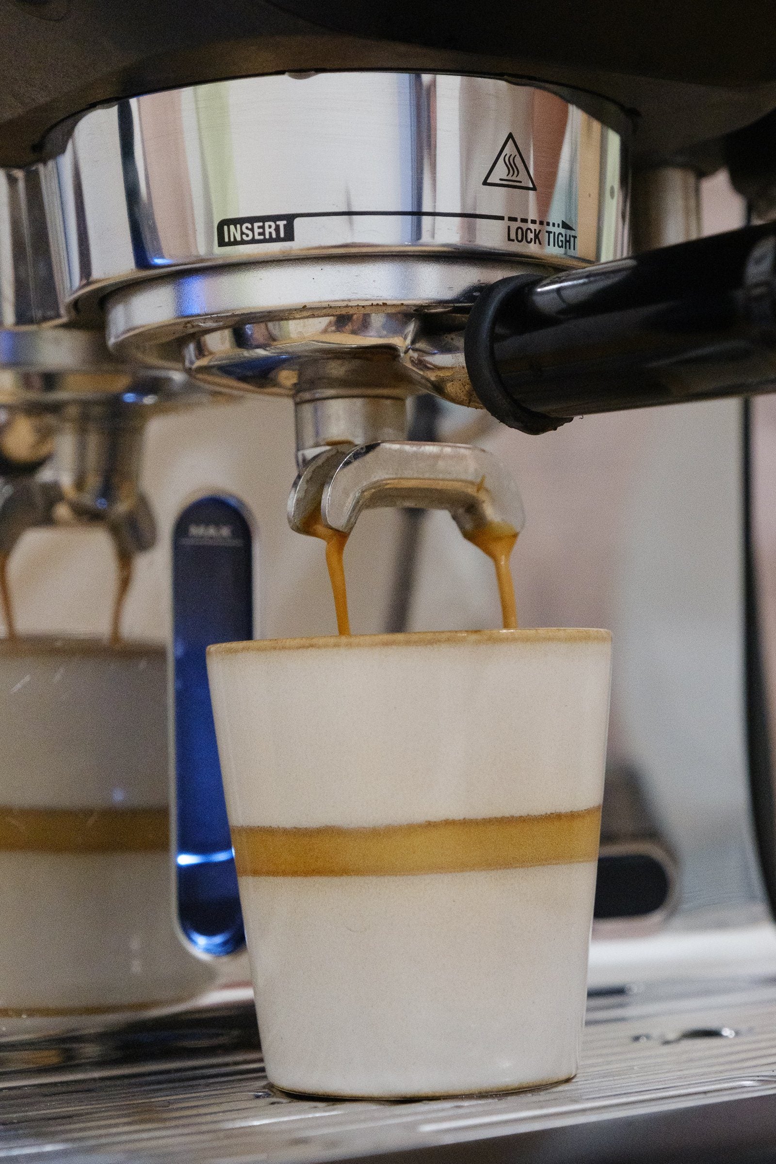 Espresso läuft aus dem Siebträger in eine Keramiktasse